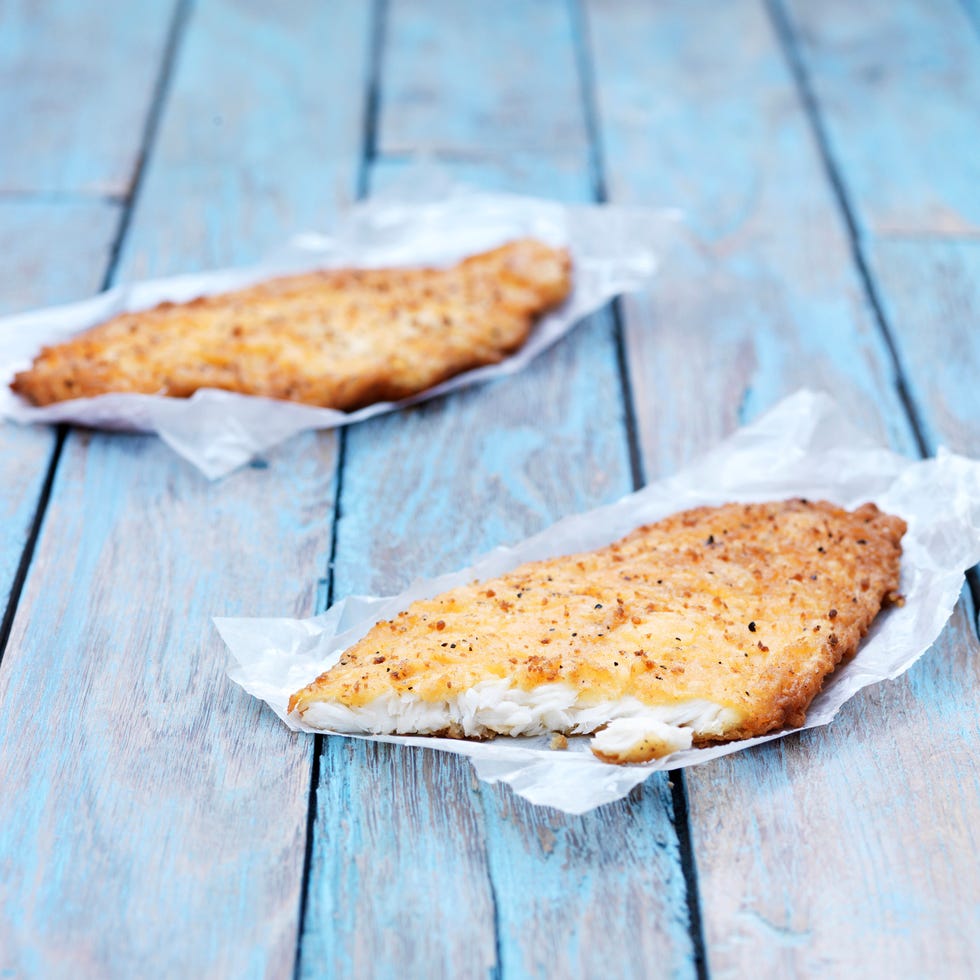 two fried breaded flounder fish pieces on wooden table